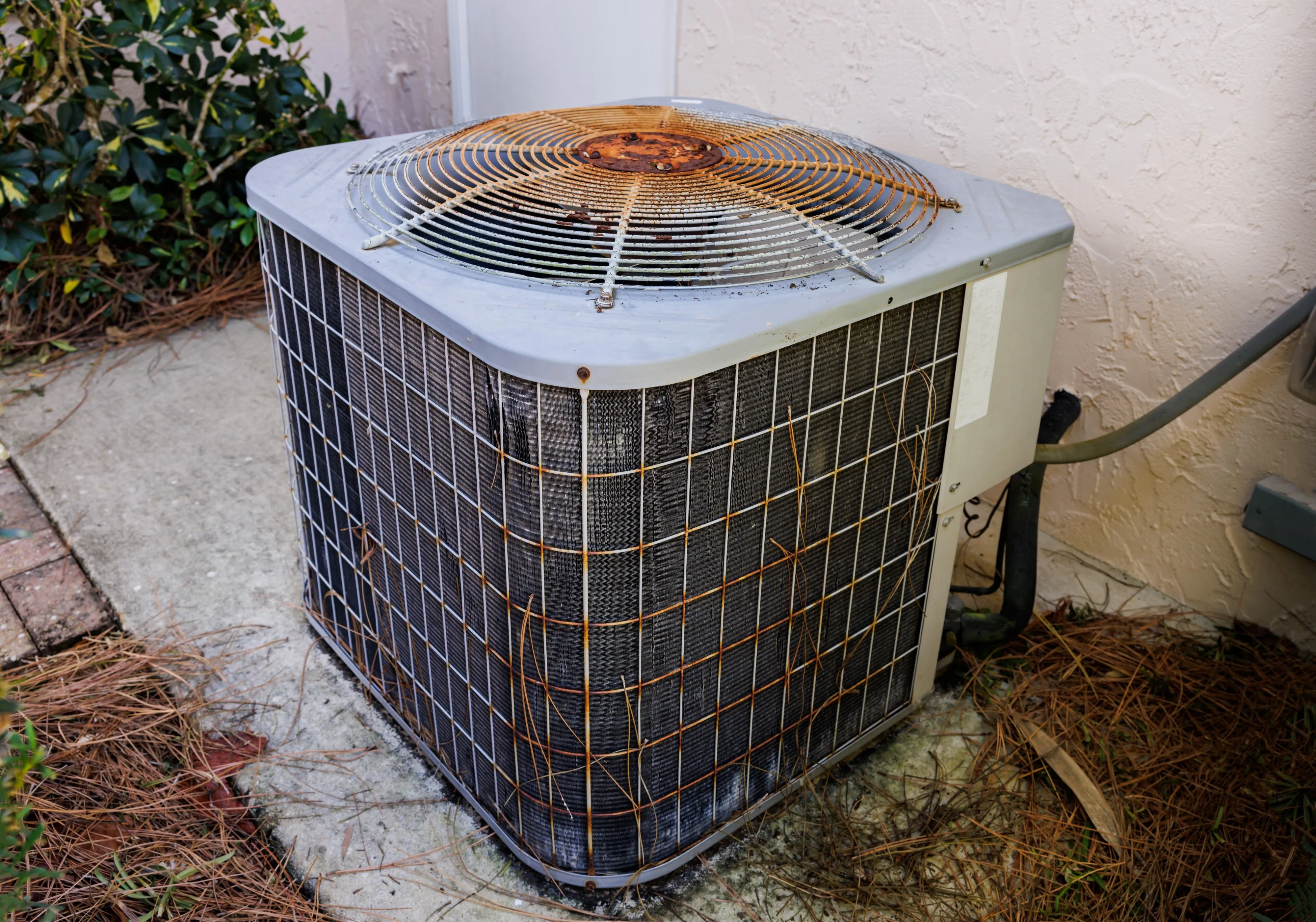 Weathered residential AC unit showing signs of aging with rust on the fan grille, typical of units approaching end of service life