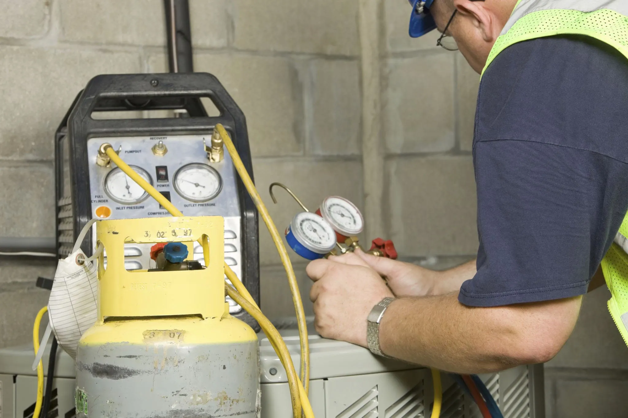 HVAC technician using refrigerant recovery equipment with gauges attached, demonstrating proper EPA-compliant refrigerant handling procedures