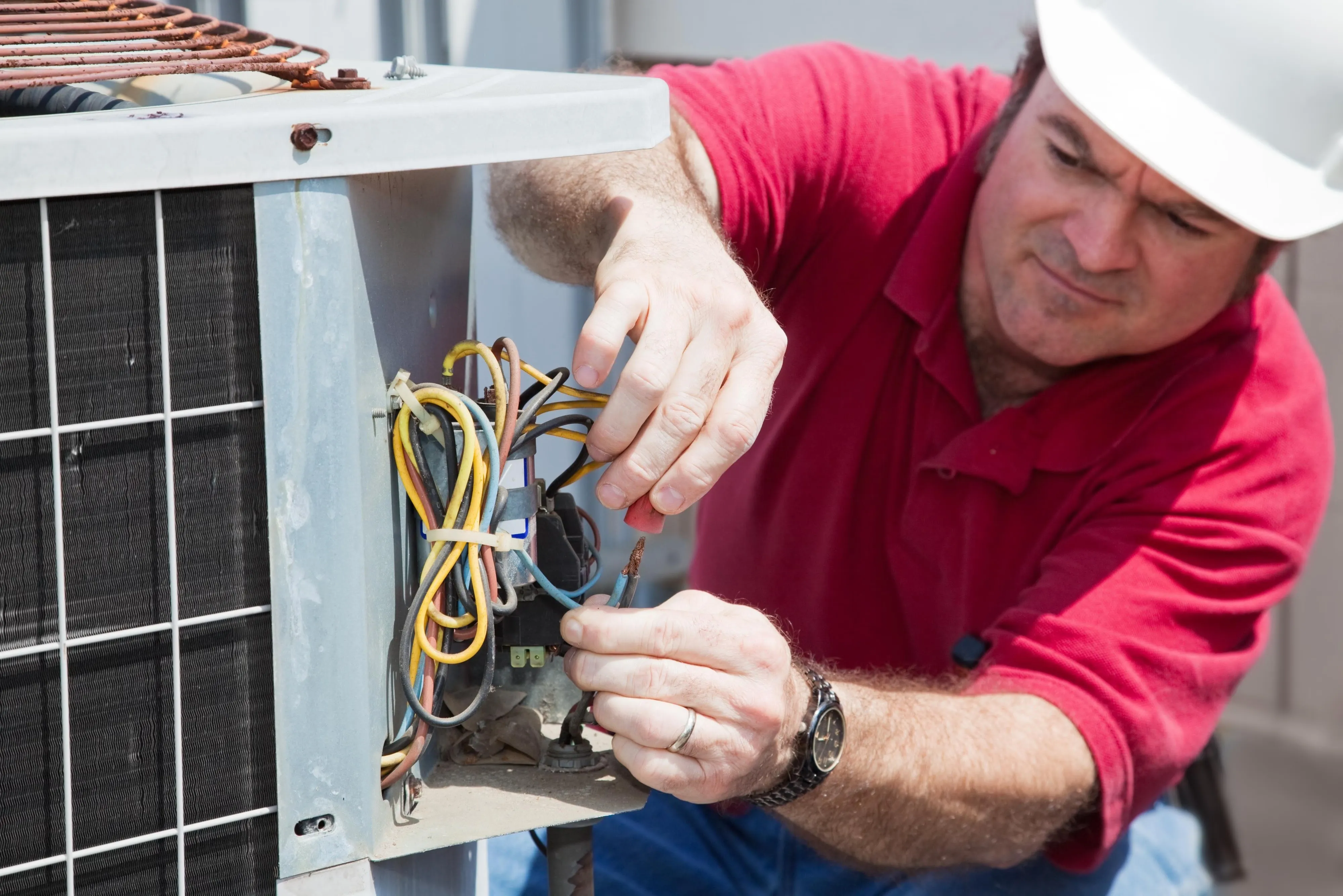 HVAC technician carefully working on electrical components inside an air conditioning unit, demonstrating precise diagnostic and repair work